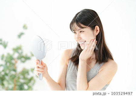 笑顔で鏡を見る女性　ビューティー 103529497