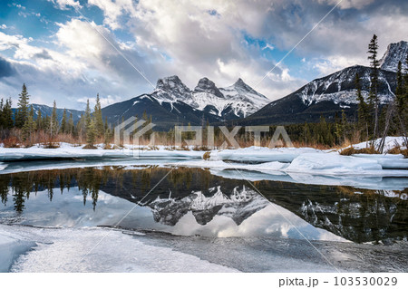 Three Sisters Mountains with snow covered on frozen bow river reflection in the morning on winter 103530029