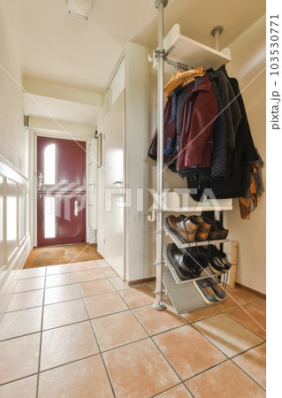 a room with some clothes hanging on the wall and a door in the corner to the floor is tileed 103530771
