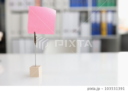 Blank pink sticky note on desktop closeup 103531391