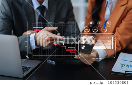 Businessman hand Project manager working and update tasks and Gantt chart scheduling virtual diagram.with smart phone, tablet and laptop in office. Businessman hand Project manager working and update tasks and Gantt chart scheduling virtual diagram.with smart phone, tablet and laptop in office. 103536801