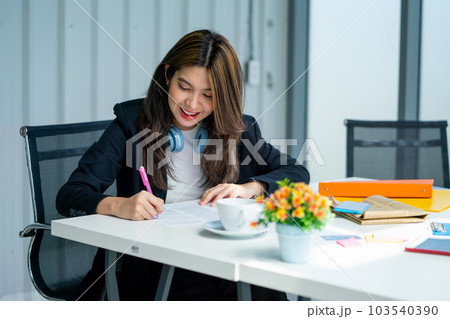 Close up pretty young business woman use pen to write and note on paper in office with happy emotion Close up pretty young business woman use pen to write and note on paper in office with happy emotion 103540390