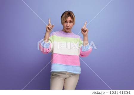 blond young woman demonstrates with her hands on the free space of the wall on a purple background blond young woman demonstrates with her hands on the free space of the wall on a purple background 103541851