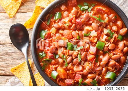 Frijoles charros is a traditional Mexican dish made of pinto beans stewed with onion, garlic, and bacon closeup on the bowl. Horizontal top view 103542086