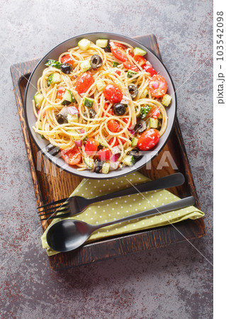 Vegetarian spaghetti salad with fresh vegetables and olives close-up in a bowl. Vertical top view 103542098