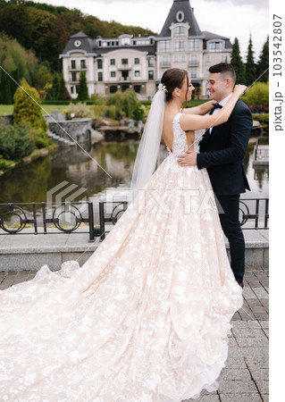 Side view of groom hug his bride and kiss. Elegant wedding dress.  103542807