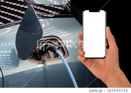 Hand with smartphone on a background of electric car . White screen, you can add your content here.. 103543714