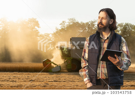 Farmer with digital tablet on a background of harvester. 103543758