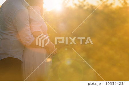 Pregnant woman stands embracing with a man 103544234