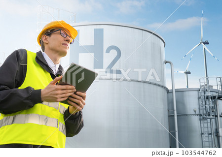 Engineer with tablet computer on a background of green Hydrogen factory. 103544762