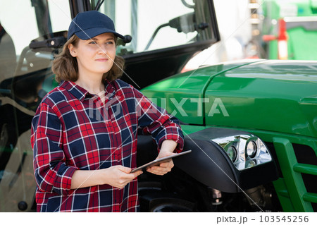 Farmer with a digital tablet on the background of an agricultural tractor 103545256