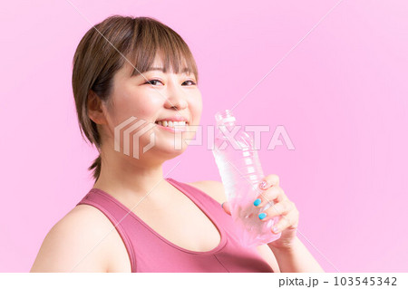 ペットボトルの水を手に持つ豊満な若い女性　プラスサイズモデル　イメージ 103545342