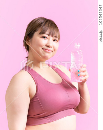 ペットボトルの水を手に持つ豊満な若い女性　プラスサイズモデル　イメージ 103545347