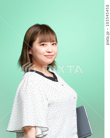タブレットを小脇に抱える若い女性 ビジネスカジュアル タブレットを小脇に抱える若い女性 ビジネスカジュアル 103545458