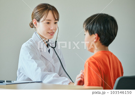 聴診器をお腹に当てて診察する若い女性医師 103546150