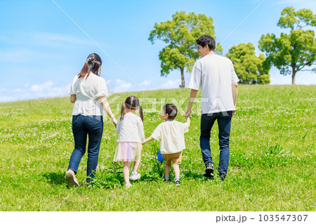 青空の草原を散歩する家族 103547307