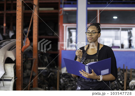 African american worker woman wear spectacles crossed arms holding clipboard standing in factory African american worker woman wear spectacles crossed arms holding clipboard standing in factory 103547728