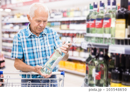 mature senor choosing alcoholic drinks in supermarket 103548650