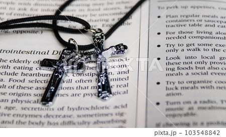 Shiny metal cross with black sling on old book to recall the kindness of Jesus Christ for all of Christian Shiny metal cross with black sling on old book to recall the kindness of Jesus Christ for all of Christian 103548842