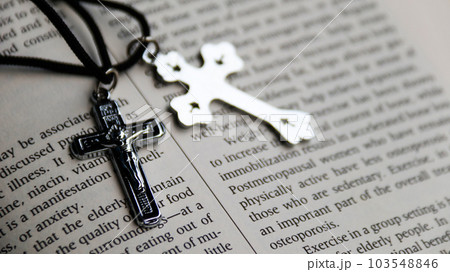 Shiny metal cross with black sling on old book to  recall the kindness of Jesus Christ for all of Christian Shiny metal cross with black sling on old book to  recall the kindness of Jesus Christ for all of Christian 103548846