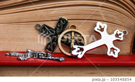 Shiny metal cross on old book to  recall the kindness of Jesus Christ for all of Christian                                103548854