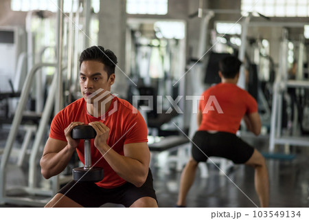 Asian man biceps squat exercise by dumbbell in fitness gym 103549134