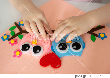 A blogger girl makes a felt craft for Valentine's Day in the shape of a heart. The concept of children's creativity and handmade. A blogger girl makes a felt craft for Valentine's Day in the shape of a heart. The concept of children's creativity and handmade. 103553206