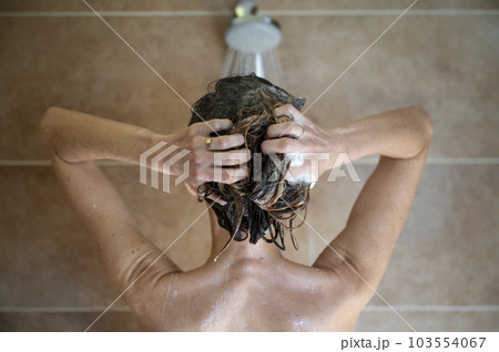 View from behind of a young woman washing her hair with shampoo 103554067