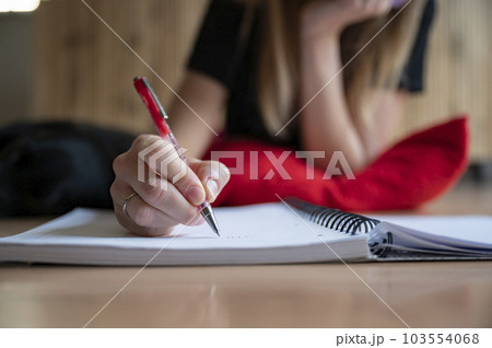 Low angle closeup view of female hand writing in spiral notebook 103554068