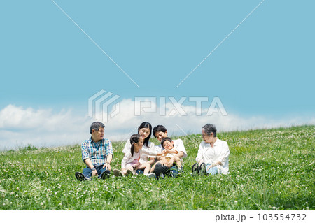 土手でのんびり談笑する家族 103554732