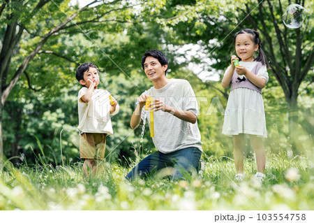 公園で子供とシャボン玉で遊ぶ若いパパ 103554758