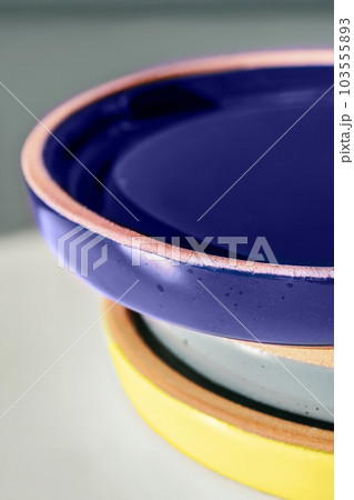 A large stack of ceramic cups in pastel colors. 103555893