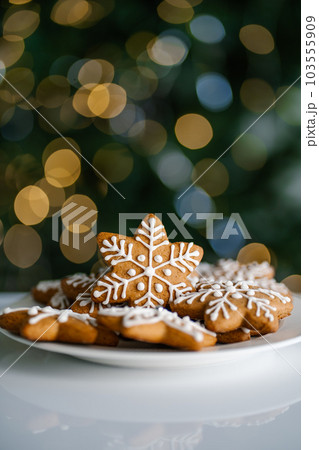 Ginger Christmas cookies on the background of a Christmas tree with lights. Ginger Christmas cookies on the background of a Christmas tree with lights. 103555909