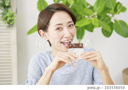 自宅で板チョコを食べる女性　カメラ目線 103556050