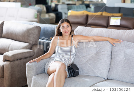 Smiling girl choosing upholstered furniture for home in store Smiling girl choosing upholstered furniture for home in store 103556224