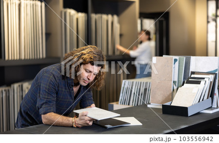 Male customer choosing kitchen ceramic tile in building store 103556942