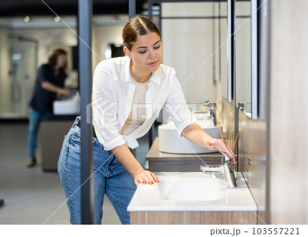 Smiling woman inspects and chooses new kitchen or bath tap faucet at hardware store Smiling woman inspects and chooses new kitchen or bath tap faucet at hardware store 103557221