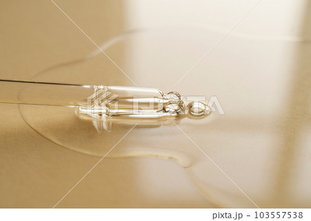 Pipette with oil or serum on a golden background. 103557538