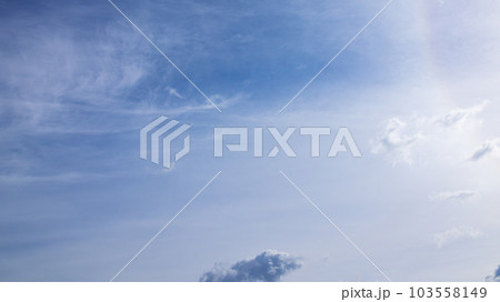 昼の青空に流れる雲と太陽による彩光 103558149