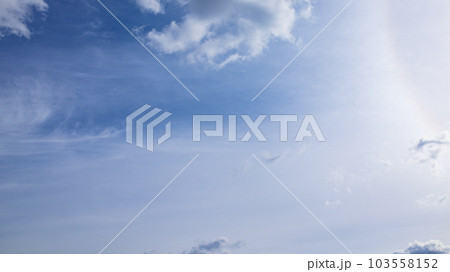 昼の青空に流れる雲と太陽による彩光 103558152
