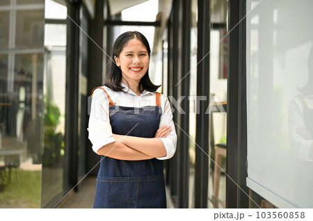 Successful Asian female restaurant or coffee shop owner stands in front of the entrance door Successful Asian female restaurant or coffee shop owner stands in front of the entrance door 103560858