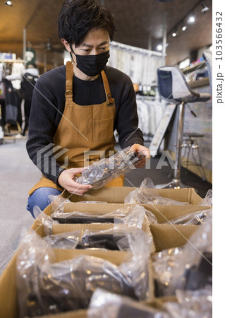 店内でお店に届いた商品をチェックする男性スタッフ 店内でお店に届いた商品をチェックする男性スタッフ 103566432