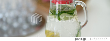 Drink with lemon slices and cucumber in jug on table Drink with lemon slices and cucumber in jug on table 103566627