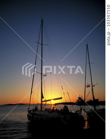 エーゲ海に沈む夕日を受けたクルーザーヨットのシルエット 103567558