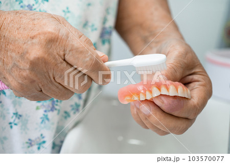 Asian elderly woman patient holding to use denture, healthy strong medical concept. 103570077