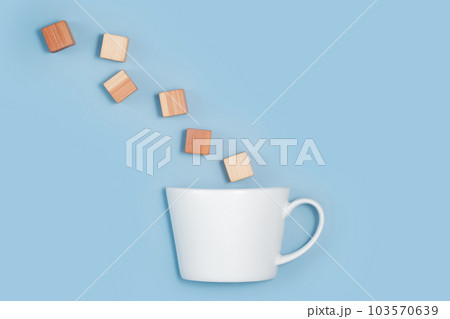 blank wooden cubes falling into a white cup on blue background. Minimalistic abstract concept representation of building creating and diversity. Top view flat lay copy space 103570639