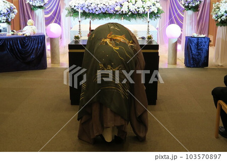 祭壇にお辞儀をする住職 103570897