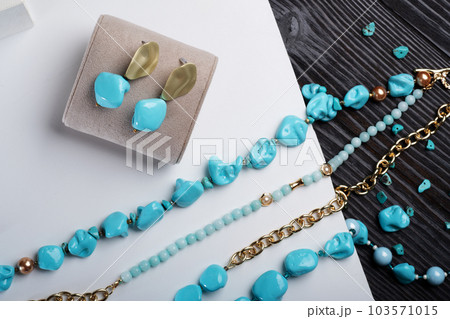 author collection jewelry with azure gemstones, pearls and chain demonstrated at white  background.  fashion and jewelry concept. flat lay 103571015