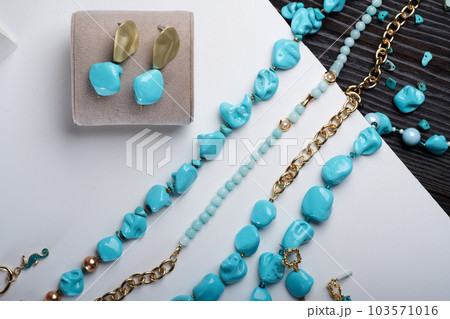 author collection jewelry with azure gemstones, pearls and chain demonstrated at white  background.  fashion and jewelry concept. flat lay 103571016