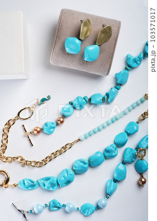 author collection jewelry with azure gemstones, pearls and chain demonstrated at white background.  fashion and jewelry concept. flat lay 103571017